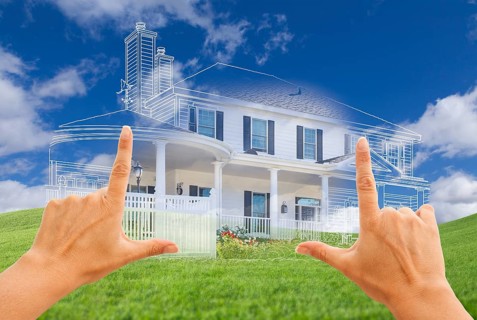 Female hands framing beautiful custom house drawing and ghosted house above grass field