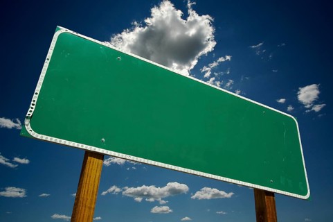 Blank green road sign on dramatic blue sky with clouds