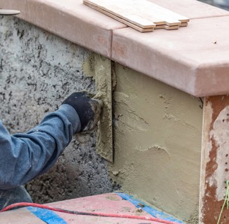 Tile worker applying cement with trowel at pool construction site