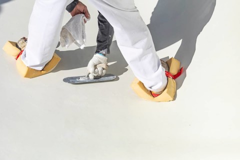 Worker wearing sponges on shoes smoothing wet pool plaster with trowel