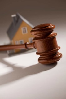 Gavel and model home on gradated background with selective focus