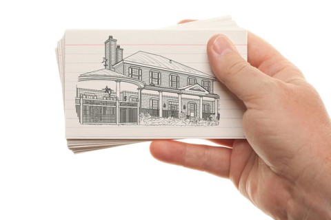 Male hand holding stack of flash cards with house drawing isolated on a white background