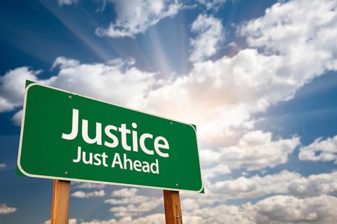 Justice just ahead green road sign with dramatic clouds