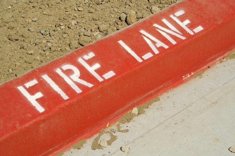 Close-up of red painted curb with fire lane text