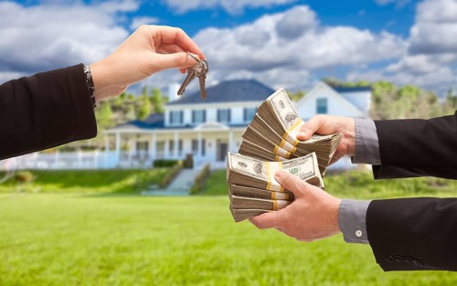 Man handing woman thousands of dollars for keys in front of house