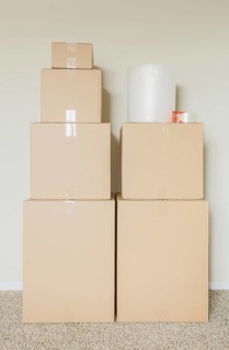 Variety of packed moving boxes with materials in empty room against wall