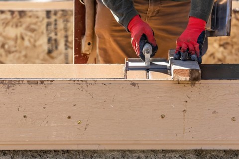 Construction worker using hand groover on wet cement forming coping around new pool