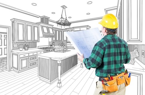 Male contractor with hard hat and plans looking at custom kitchen drawing on white