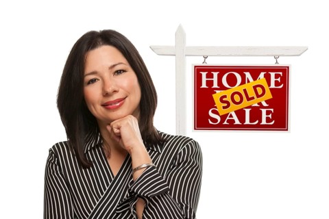 Ethnic woman in front of sold home for sale real estate sign isolated on a white background