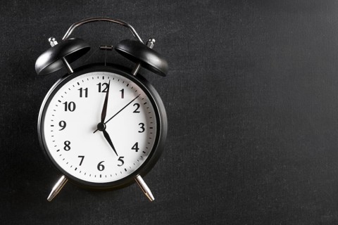 Alarm clock showing 5 o clock against black background