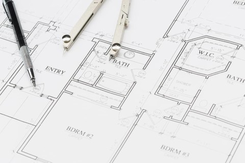 Engineer pencil and compass resting on custom house plans
