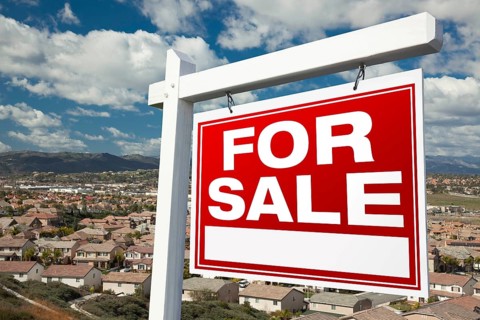 For sale real estate sign with elevated housing community view