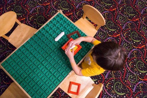 Overhead of mixed-race boy sitting at a work table playing with building blocks toys