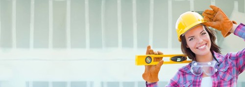 Female contractor wearing hard hat against dywall banner background with ladder