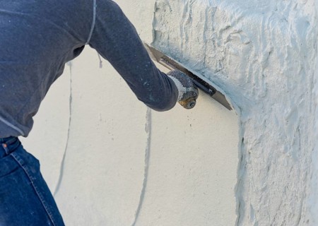 Worker smoothing wet pool plaster with trowel