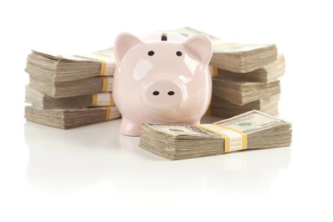 Pink piggy bank with stacks of hundreds of dollars isolated on a white background