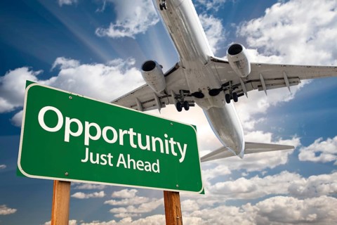 Opportunity green road sign and airplane above with dramatic blue sky and clouds