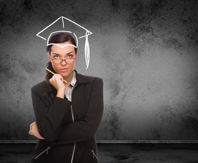 Graduation cap drawn on head of young adult woman with pencil in front of wall with copy space