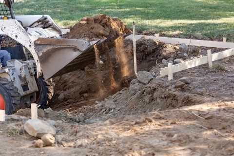 Small bulldozer digging in yard for pool installation