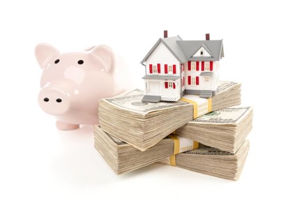Small house and piggy bank with stacks of hundred dollar bills isolated on a white background