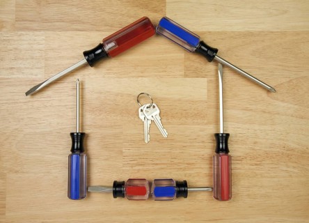 House shaped by screwdrivers and keys on a wood background