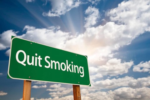 Quit smoking green road sign with dramatic clouds