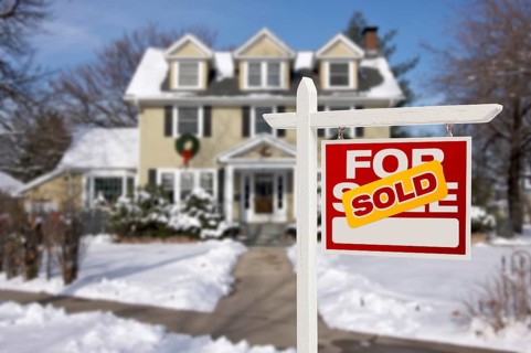 Sold home for sale real estate sign in front of beautiful new house in the snow