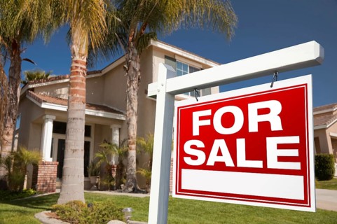 For sale real estate sign in front of house