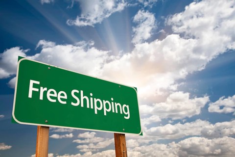 Free shipping green road sign over dramatic sky