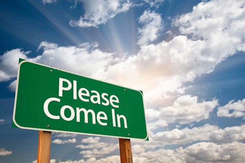 Please come in green road sign against clouds and sunburst