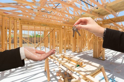 Handing over the keys on site inside new home construction framing