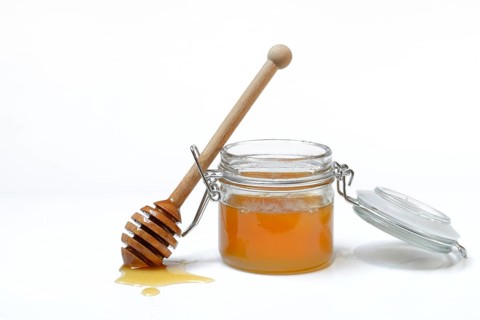 Bienenhonig in Glas und Honigloeffel