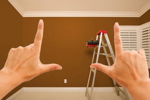Hands framing brown painted room wall interior with ladder