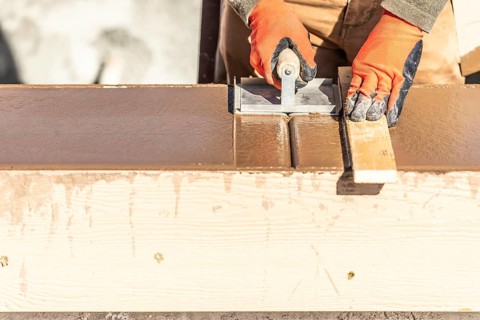 Construction worker using hand groover on wet cement forming coping around new pool