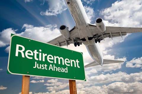 Retirement green road sign and airplane above with dramatic blue sky and clouds