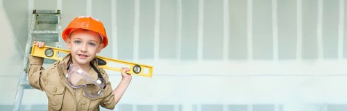 Cute young boy dressed as contractor holding level against dywall banner background with ladder