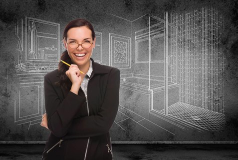 Young adult woman with pencil in front of bathroom design drawing on wall