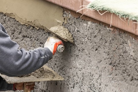 Tile worker applying cement with trowel at pool construction site