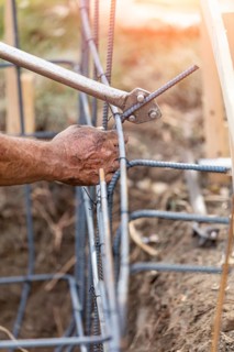 Worker using tools to bend steel rebar at construction site