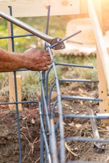 Worker using tools to bend steel rebar at construction site