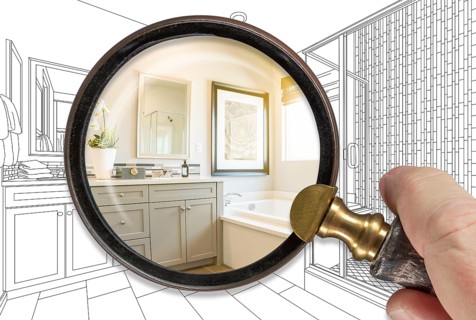 Hand holding magnifying glass revealing finished bathroom build over drawing