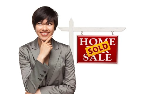 Ethnic woman in front of sold home for sale real estate sign isolated on a white background