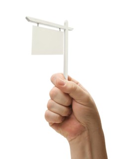 Blank real estate sign in male fist isolated on a white background