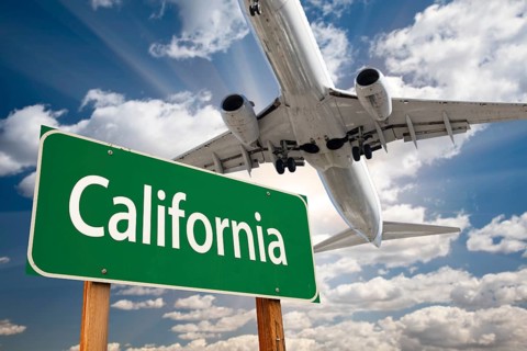 California green road sign and airplane above with dramatic blue sky and clouds