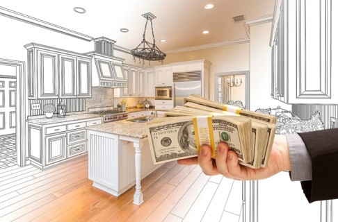 Hand handing stacks of money over custom kitchen design drawing and photo combination