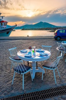 Street cafe table with ready for dinner on quay of Naousa town port in famous tourist attraction Paros island