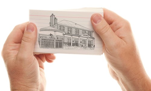 Male hand holding stack of flash cards with house drawing isolated on a white background