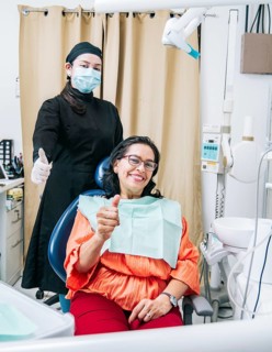 Dentist with thumb up patient in office
