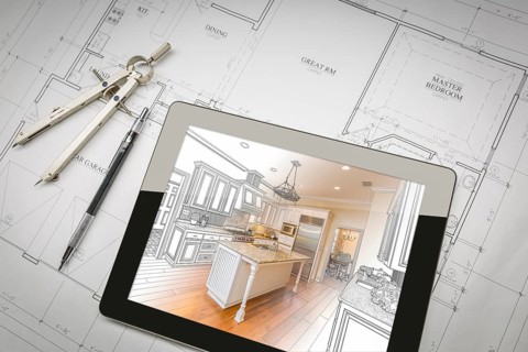 Computer tablet showing kitchen illustration sitting on house plans with pencil and compass