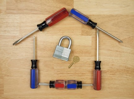 House shaped by screwdrivers with lock and key on a wood background